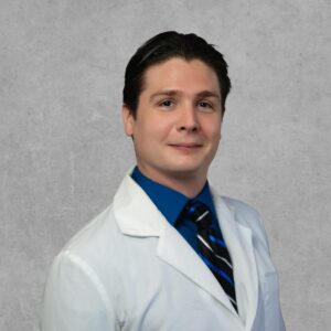 Joshua Johnson, medical provider at Optima Medical in Queen Creek, Arizona, wearing a white coat and blue tie.