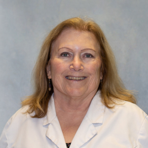 Julie Townsend, healthcare provider at Optima Medical in Tucson, Arizona, wearing a white coat and smiling against a gray background.