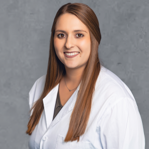 Madison M Schelhaas, healthcare provider at Optima Medical in Queen Creek, Arizona, smiling in a white coat.