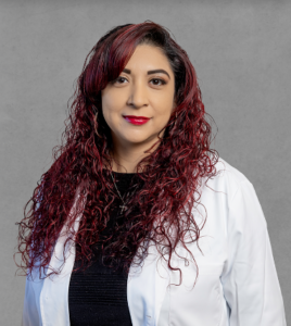 Elizabeth Franco, healthcare provider at Optima Medical in Sierra Vista, Arizona, wearing a white coat with long curly red hair.
