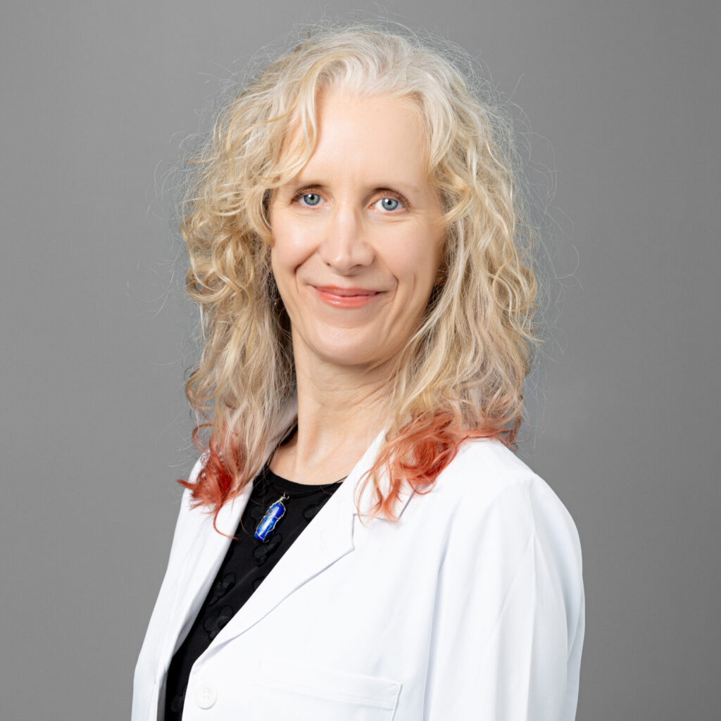 Tess Barnes, medical provider at Optima Medical in Prescott, Arizona, wearing a white coat and smiling for professional photo.