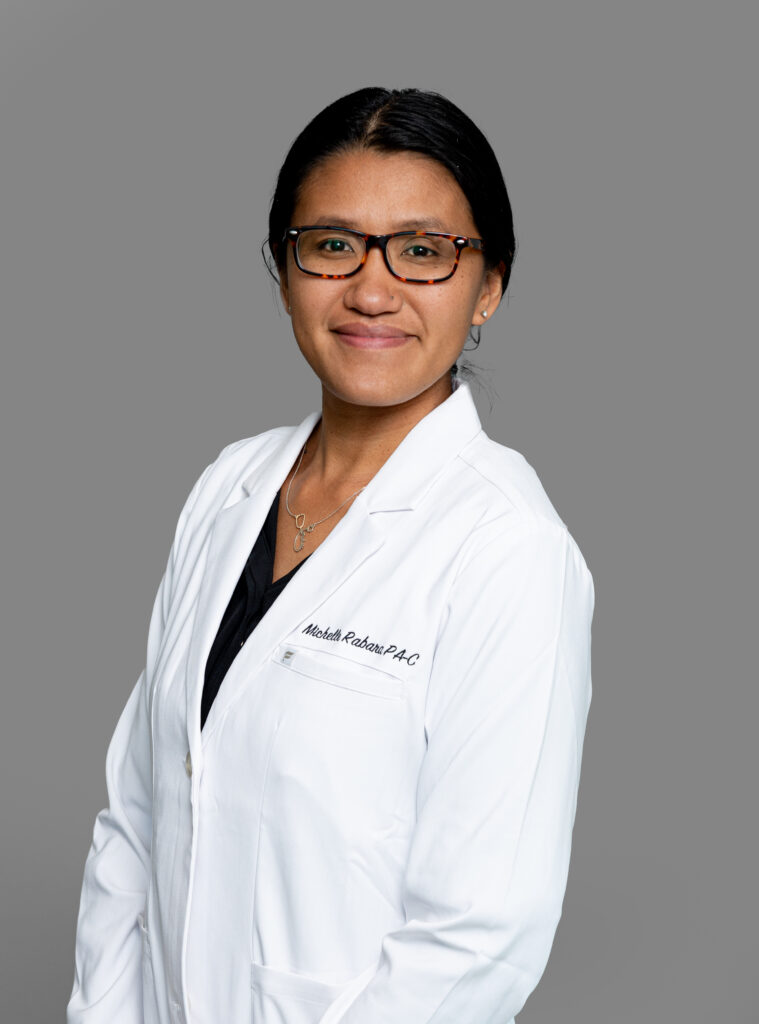 Michelle Rabara, healthcare provider at Optima Medical in Sierra Vista, Arizona, wearing glasses and a white medical coat.